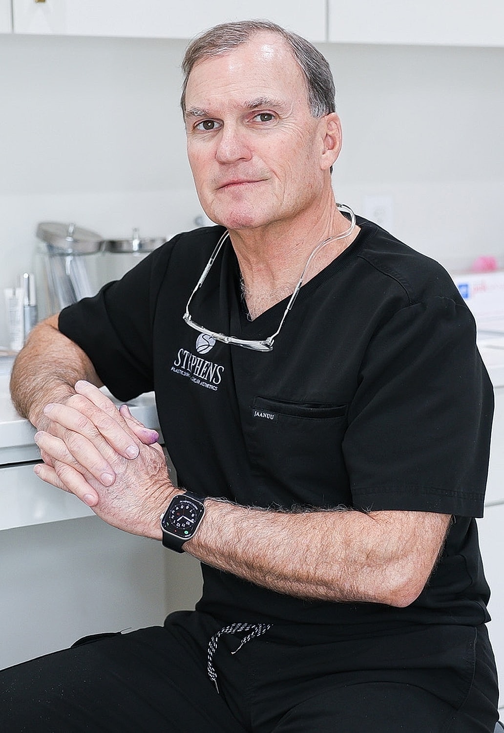 Doctor in a black scrubs, seated at desk.