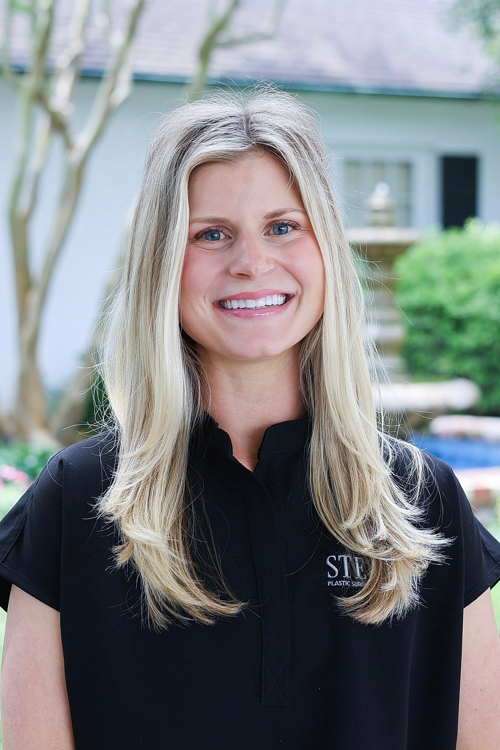 Smiling woman in professional attire outdoors.