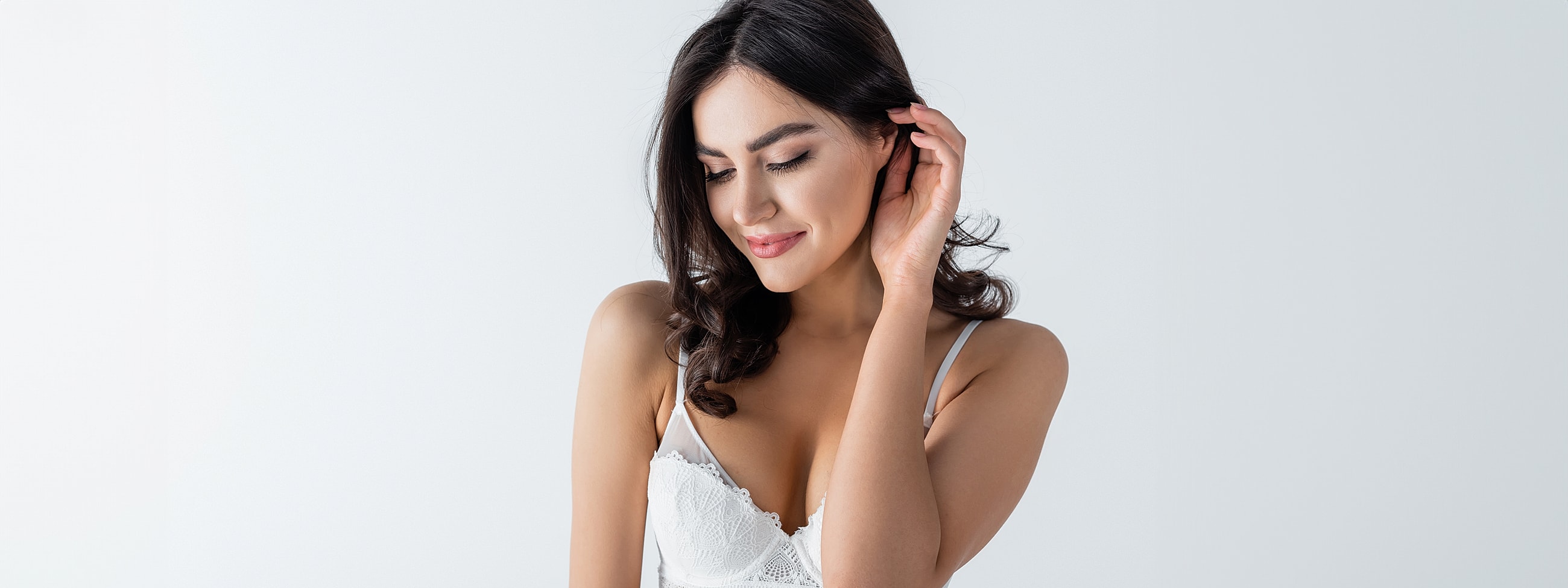 Woman in white lingerie with soft expression.